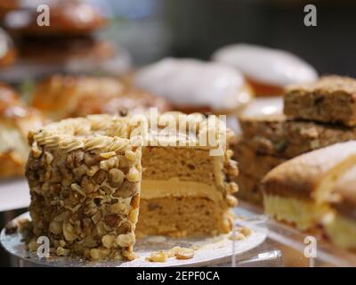 Sélection de gâteaux frais, gâteau au café et aux noix, gâteaux Victoria Sponge, petits pains glacés, beignets et pâtisseries à vendre au café-restaurant Banque D'Images