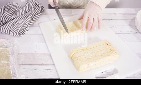 Étape par étape. Coupe de fudge de canne à sucre fait maison sur un tableau de découpe blanc. Banque D'Images