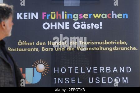 Koserow, Allemagne. 27 février 2021. Michael Raffelt, exploitant de l'hôtel Hanse-Kogge, se dresse à Koserow devant une affiche avec le slogan 'No Spring Eveil without guests! Sur l'île de vacances d'Usedom, les hôteliers ont lancé une campagne d'affiches le même jour, soulignant les conséquences imminentes de mois de fermetures forcées. Credit: Stefan Sauer/dpa/Alay Live News Banque D'Images