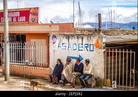 1 chien, colombien 3 hommes, 1 femme assis sur le banc, en attente. 1 dans le poncho traditionnel à chapeau, Ruana. Asadero signe Boyacá département, Colombie, Amérique du Sud Banque D'Images