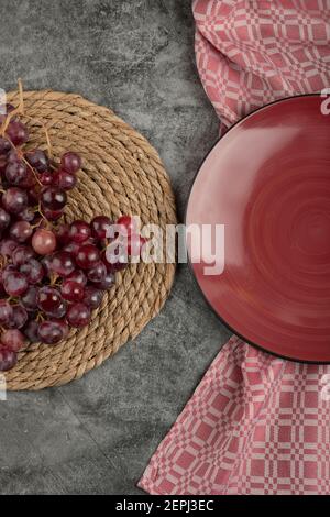 Grappe de raisins rouges et assiette rouge vide sur marbre surface Banque D'Images