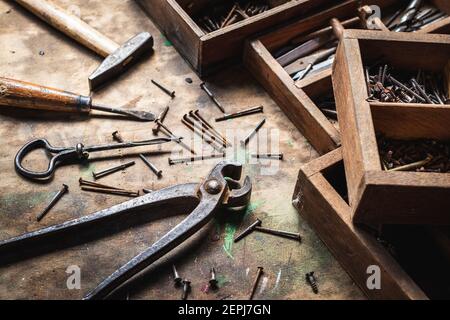 Outil de travail vintage et boîte à outils sur table en bois. Pinces, marteau, tournevis, boulon, vis et autres outils à main en atelier Banque D'Images