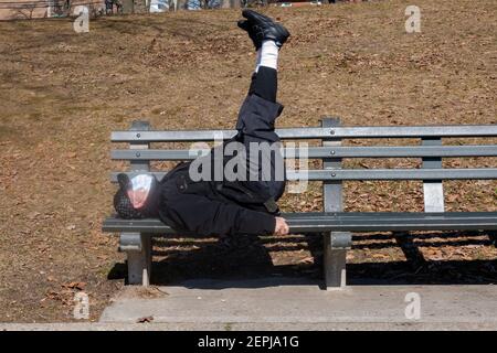 Un senior américain chinois fait des exercices d'étirement et d'estomac tout en étant allongé sur un banc à Kissena Park, Flushing, New York City. Banque D'Images