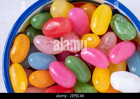 Grains de gelée doux dans un bol en céramique sur fond blanc. Bonbons colorés aux arômes de fruits mélangés. Vue de dessus, gros plan. Banque D'Images