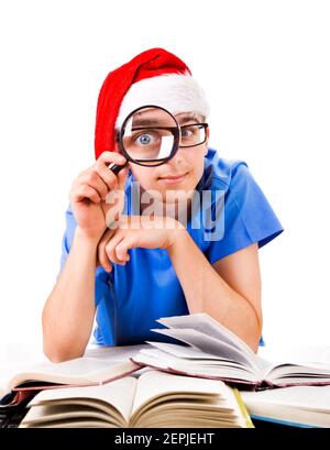 Surpris étudiant dans le chapeau de père Noël avec la loupe sur le Arrière-plan blanc Banque D'Images
