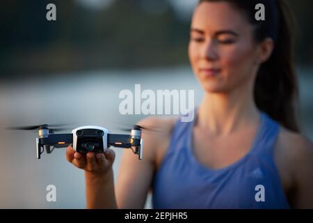 Jeune belle femme contrôle un quadcopter blanc par télécommande avec une tablette. Focalisé sur le drone, le pilote est hors de point. Enseignement du vol Banque D'Images