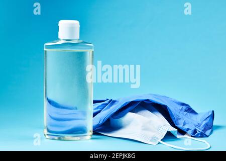 désinfectant pour les mains vierge avec masque facial et gants en latex sur fond bleu. espace de copie. concept de symbole covid-19 Banque D'Images