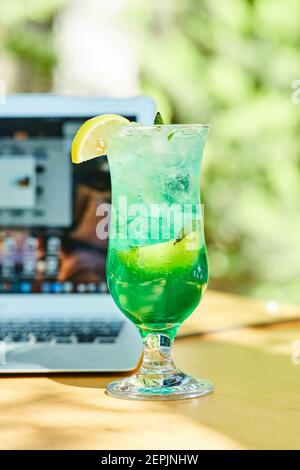Une limonade de fruits à côté d'un ordinateur portable sur une table en bois Banque D'Images