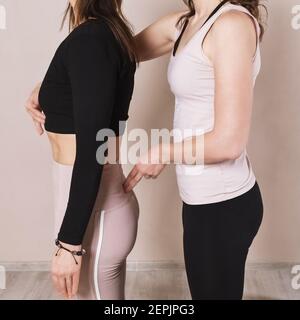 Une femme instructeur de yoga corrige un étudiant debout dans la pose Tadasana, gros plan. Banque D'Images