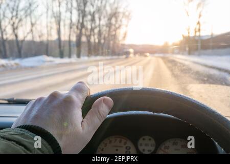 la main du conducteur sur le volant de la voiture, qui est aveuglée par le soleil du matin Banque D'Images