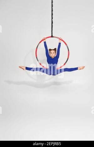 petite fille de gymnaste en vêtements de sport faisant la ficelle sur un arceau d'antenne Banque D'Images