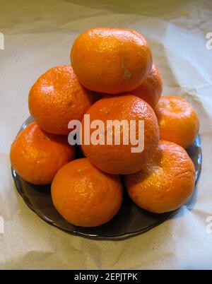 Un bouquet de mandarines orange juteuses sur une assiette noire Banque D'Images