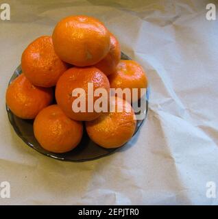 Un bouquet de mandarines orange juteuses sur une assiette noire Banque D'Images