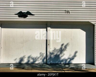 Shadow rampera à la porte d'un garage double à numéro de maison 704 Banque D'Images