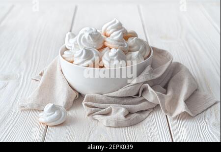 Les gâteaux de meringue blancs sur l'assiette sont enveloppés dans une serviette en lin. Banque D'Images