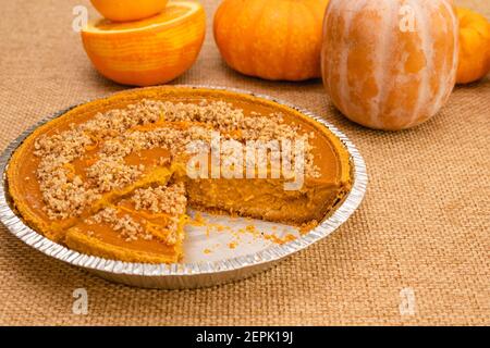 Tarte à la citrouille maison fraîchement cuite, décorée de noix écrasées et zeste d'orange gros plan sur fond rustique Banque D'Images