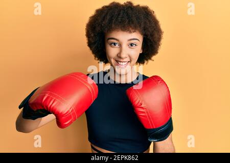 Jeune fille sportive hispanique utilisant des gants de boxe souriant avec un sourire heureux et frais sur le visage. Montrant les dents. Banque D'Images