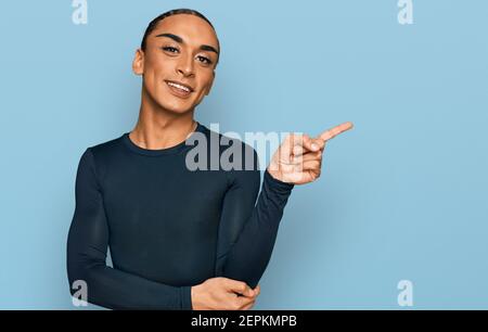 Homme transgenre hispanique portant un maquillage et des cheveux longs vêtements décontractés souriants souriants avec le doigt et la main le côté Banque D'Images