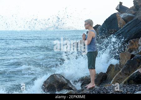 Homme méditant sur la côte de la plage de rochers Banque D'Images