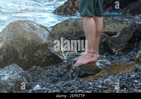 Homme jambes sur la côte de la plage de rochers Banque D'Images