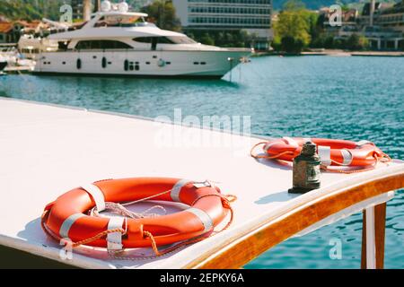 Les bouées de sauvetage se trouvent sur le toit du bateau, sur la jetée près de la vieille ville de Kotor au Monténégro, sur fond d'un grand yacht moderne amarré Banque D'Images