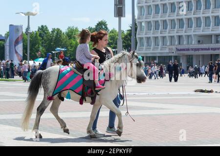 Un enfant fait une poney avec un instructeur sur la place de la ville, le jour de la Russie. Russie, Ulyanovsk 12 juin 2017 Banque D'Images