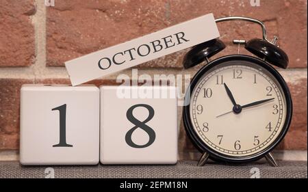 Date importante, 18 octobre, saison d'automne. Calendrier en bois sur fond de mur de briques. Réveil rétro comme concept de gestion de l'heure. Banque D'Images
