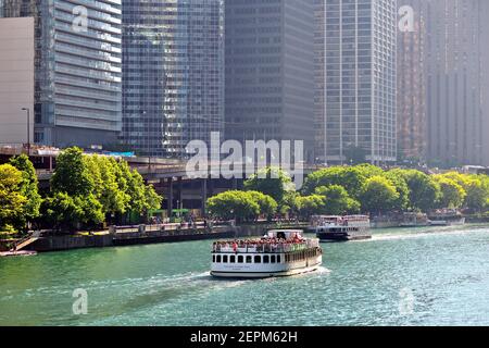 Chicago, Illinois, États-Unis. Des bateaux de tourisme passent tout en naviguant sur le fleuve Chicago à l'ombre d'une tour de condominium et de tours d'hôtel. Banque D'Images