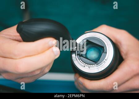 Gros plan de l'objectif de l'appareil photo pour le nettoyage des mains du photographe avec un aspirateur, un souffleur d'air ou une pompe à vide. Entretien de l'équipement de photographie Banque D'Images