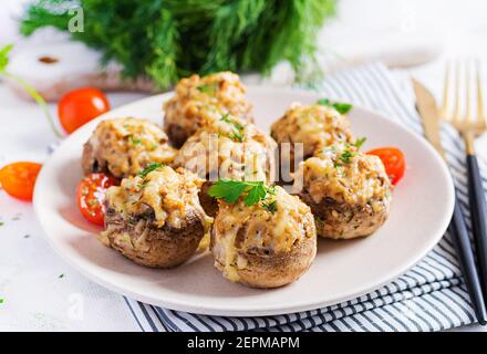 Champignons cuits farcis avec de la viande hachée au poulet, du fromage et des herbes sur une assiette légère. Banque D'Images