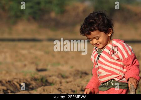 Visage souriant d'un petit enfant indien beau, portrait en plein air d'un petit garçon asiatique heureux jouant dans la ferme agricole , Inde . concept pour l'Inde Banque D'Images