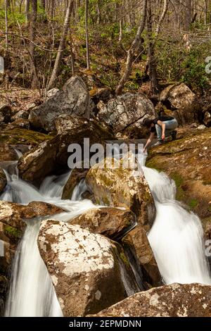 Une rancheuse tente de toucher l'eau au-dessus d'une cascade. Une longue exposition de tir dans un endroit rural en Virginie-Occidentale avec le wate de source de montagne Banque D'Images