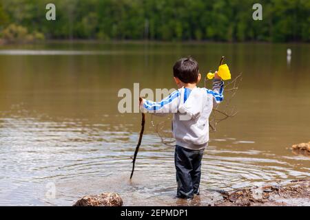 Un petit garçon d'âge préscolaire actif joue en eau peu profonde dans le petit lac des montagnes Catoctin. Son pantalon est mouillé mais encore joueur Banque D'Images