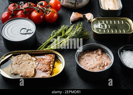 Poisson en conserve avec différents types d'assortiment de fruits de mer, sur fond noir avec des herbes et des ingrédients Banque D'Images