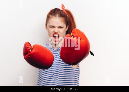 un sportif agressif avec des gants de boxe et un t-shirt rayé sur un arrière-plan clair Banque D'Images