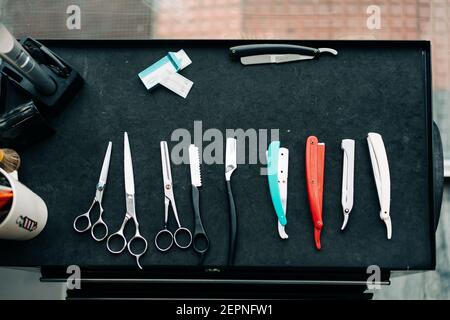 Vue de dessus des ciseaux assortis près des rasoirs droits avec tranchant lames métalliques sur la table du salon de coiffure Banque D'Images