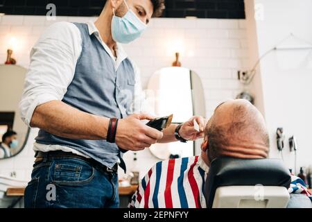 Un homme non rasé dans un masque médical et un T-shirt blanc avec 