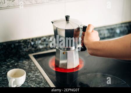 Petite personne tenant une machine à café avec plaque de cuisson en métal et plastique la cuisine de la maison est équipée d'une plaque de cuisson moderne à la lumière du jour Banque D'Images