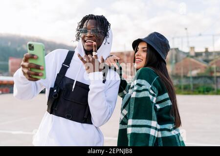 Des produits multiraciaux pour les jeunes dans des vêtements élégants qui s'empare du selfie chaussée urbaine en plein soleil Banque D'Images