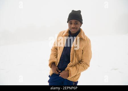 Jeune homme afro-américain portant des vêtements d'hiver debout dans la neige terrain et regarder la caméra Banque D'Images