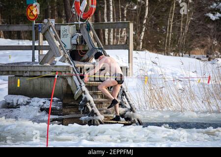 Homme descendant dans avanto ou un trou de natation de glace pour la natation d'hiver dans le district de Munkkiniemi d'Helsinki, Finlande Banque D'Images