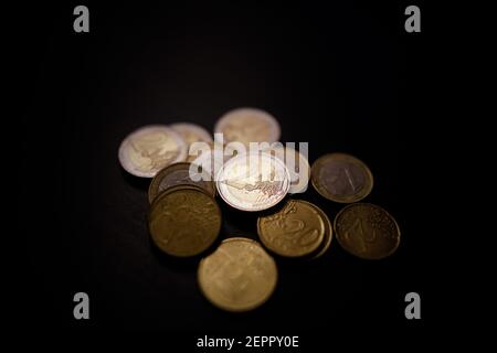 Faible profondeur de champ (mise au point sélective) et image macro avec une pièce métallique de 2 euros près d'autres pièces en euros sur fond noir. Banque D'Images