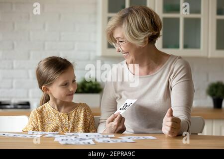 Femme âgée enseignant d'étude de mathématiques avec la jeune fille d'élève en utilisant des cartes Banque D'Images