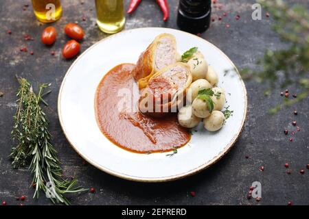 Chou farci à la viande hachée dans une sauce tomate, servi avec des pommes de terre. Plat préparé servi sur une assiette. Proposition de service, photographie culinaire. Banque D'Images