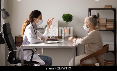 Vue latérale médecin portant un masque facial consultant un patient mature Banque D'Images