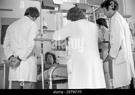 Hôpital Ward Cardiff pour enfants. Consultants debout autour du lit d'un enfant malade Banque D'Images