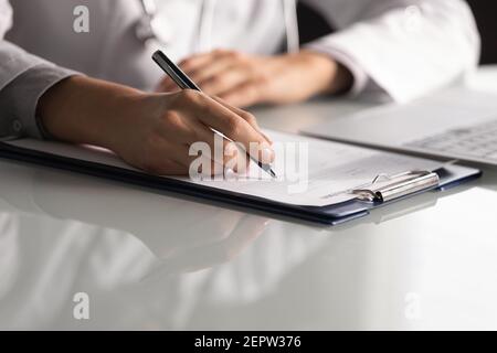 Gros plan professionnel femme médecin prenant des notes, remplissant des documents médicaux Banque D'Images