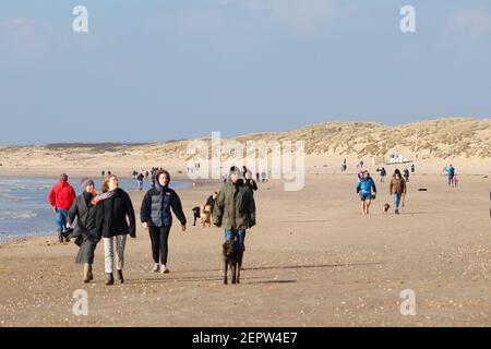 Camber, East Sussex, Royaume-Uni. 28 févr. 2021. Météo au Royaume-Uni : soleil d'hiver chaud avec vents venteux ici, à Camber Sands, dans l'est du Sussex. Beaucoup de familles et de personnes appréciant le doux temps d'hiver marchant avec des chiens le long de la plage de sable. Grand groupe de personnes appréciant l'air frais sur le sable doré. Crédit photo : Paul Lawrenson/Alay Live News Banque D'Images