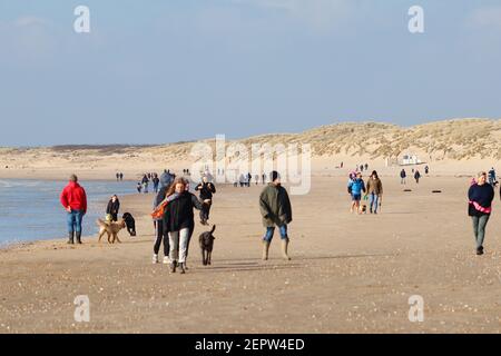 Camber, East Sussex, Royaume-Uni. 28 févr. 2021. Météo au Royaume-Uni : soleil d'hiver chaud avec vents venteux ici, à Camber Sands, dans l'est du Sussex. Beaucoup de familles et de personnes appréciant le doux temps d'hiver marchant avec des chiens le long de la plage de sable. Grand groupe de personnes appréciant l'air frais sur le sable doré. Crédit photo : Paul Lawrenson/Alay Live News Banque D'Images