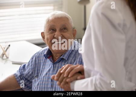 Gros plan souriant homme mûr et soignant tenant les mains Banque D'Images